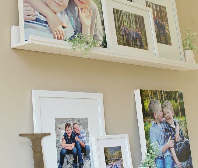 Photo gallery wall using photo ledges to cover up an ugly thermostat.