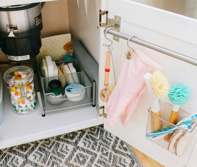 Under sink organization. Extra storage added to the inside of the cabinet door with a towel rod and acrylic organizer.