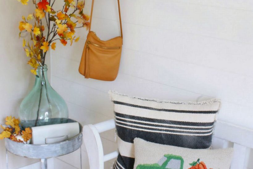 Fall front entryway decorated for fall with faux leaves and a fall pillow.