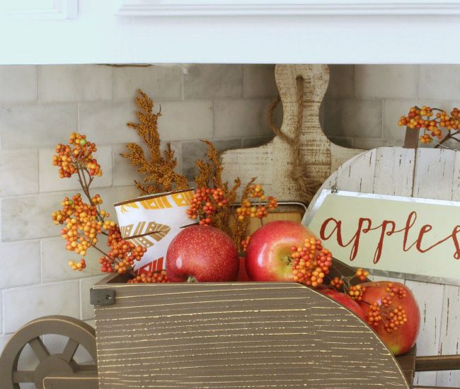 Easy fall kitchen decorating ideas. Simple ways to add some fall to your kitchen decor! Fill a small wheelbarrow with apples or other fruit for a seasonal display.