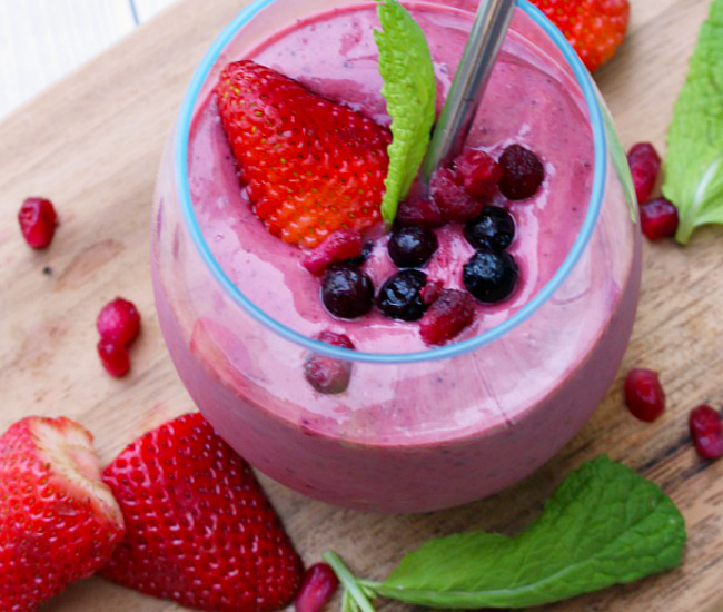 Berry green smoothie with a metal straw.