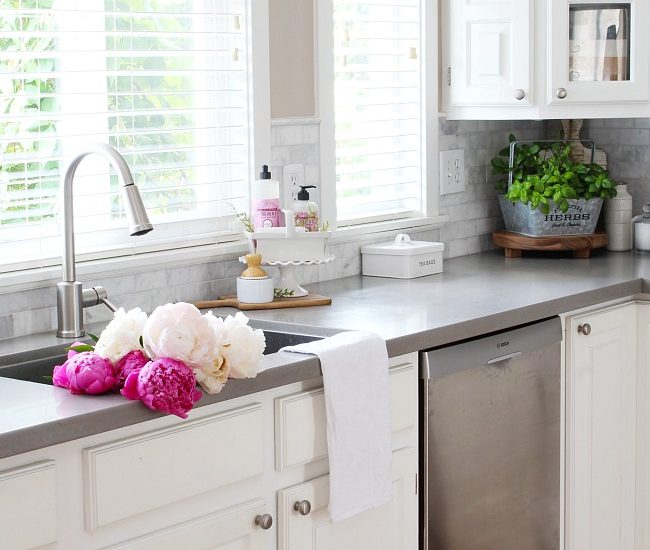 White farmhouse style kitchen with beautiful pink peonies in the sink.