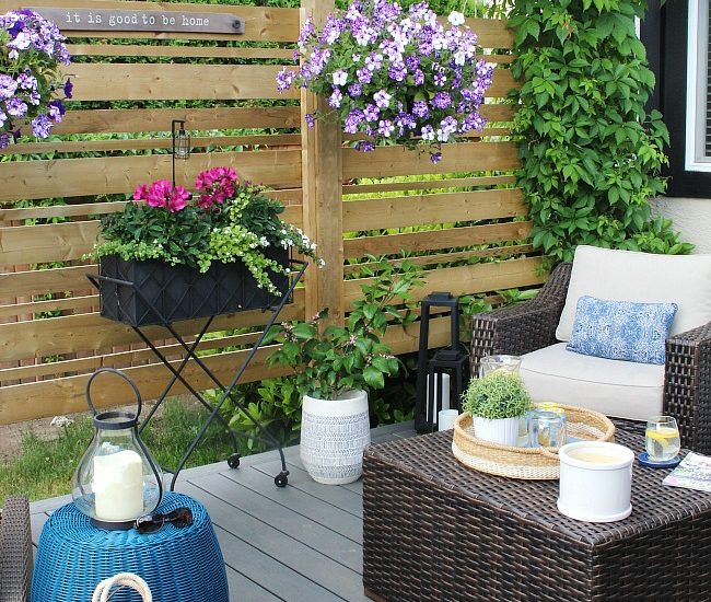 Wooden privacy screen on summer patio decorated with flowers.