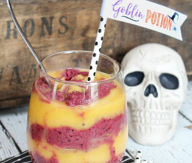 Orange and purple Halloween goblin potion smoothie in a clear glass with a fun straw topper.