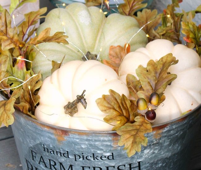 Lighted fall pumpkin bucket. Galvanized metal bucket filled with pumpkins, fall leaves, and mini lights.