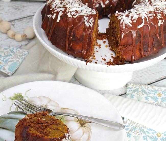 Chocolate coconut pumpkin swirl bundt cake on a cake stand with fall plates.