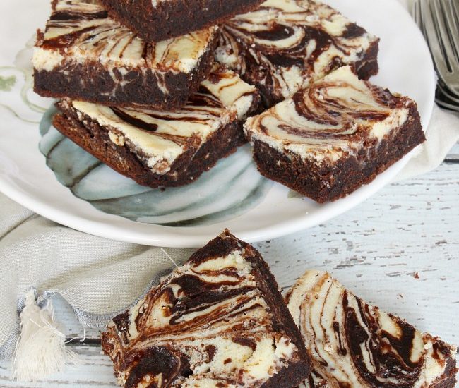 Chocolate pumpkin cream cheese swirl brownies displayed on a plate.