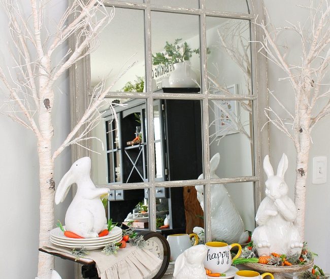 Dining room sideboard decorated for spring with white ceramic bunnies and twinkle light trees.