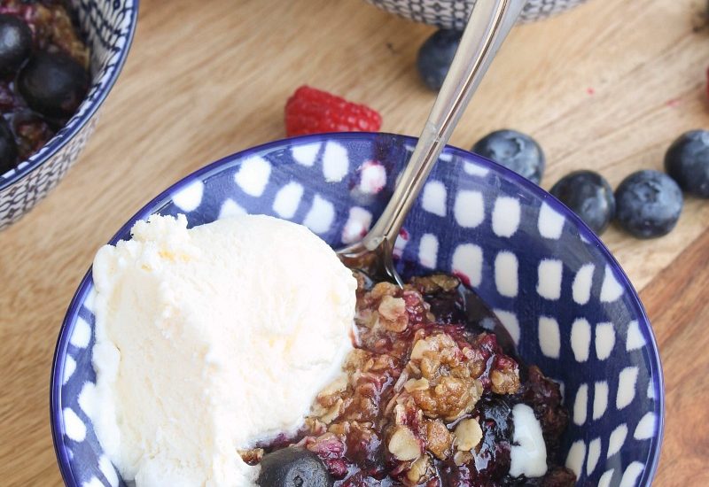 Berry crisp with ice cream in blue bowls.