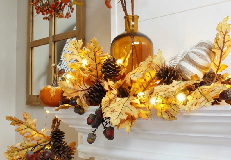 Amber glass vase used on a fall mantel with a golden oak garland and fall lights.