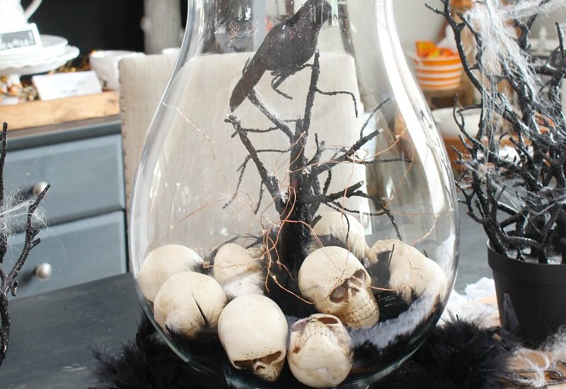 Halloween centerpiece with hurricane lantern and skulls.