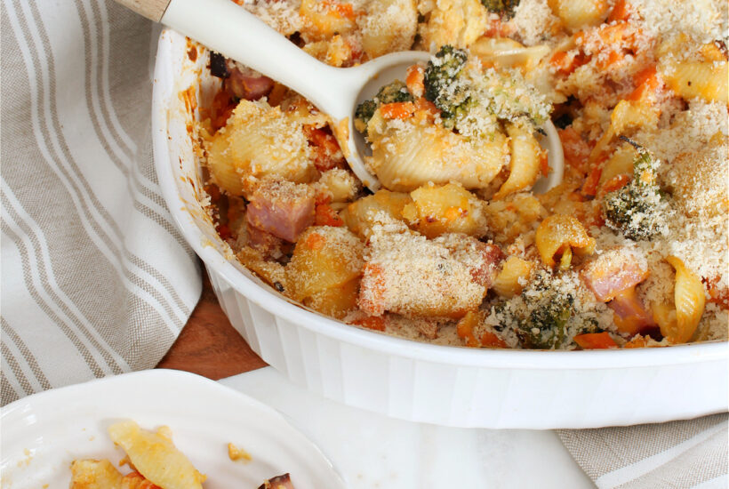 Cheesy vegetable and ham casserole in a baking dish.