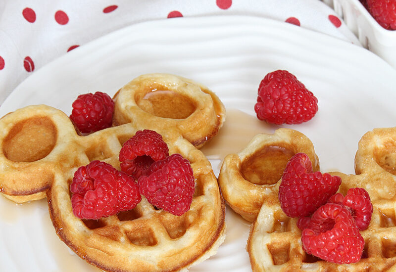 Cute mickey waffles with raspberries and syrup.