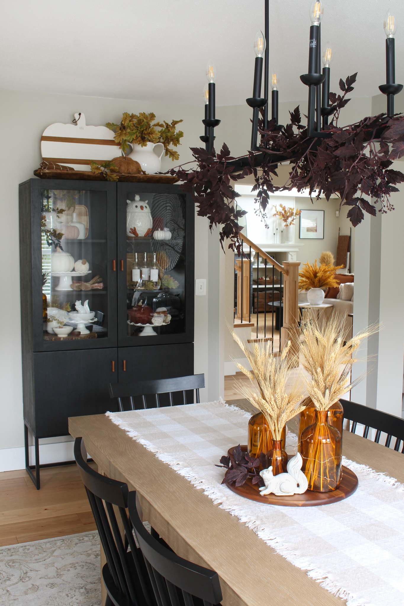 Fall dining room with wood table and black bar cabinet with fall decor pieces.