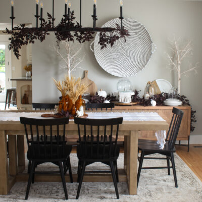 Modern dining room with wood table and side board with black chairs. Simple fall decor with wheat and plum cimicifuga garlands and branches.