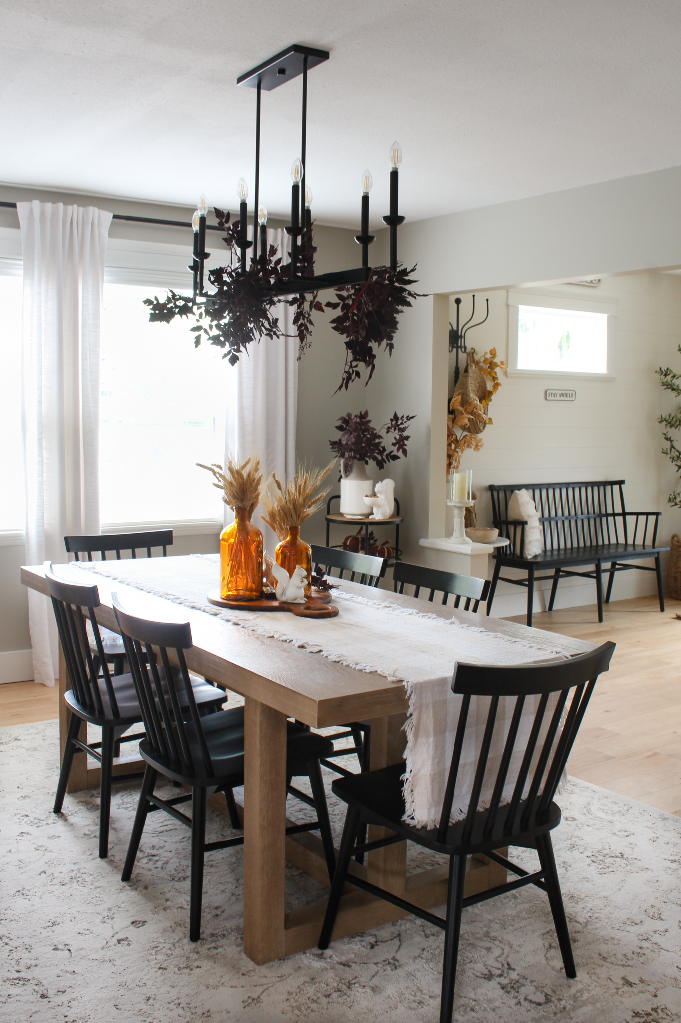 Fall dining room table with amber glass centerpiece and plum cimicifuga leaf garland over the light fixture.