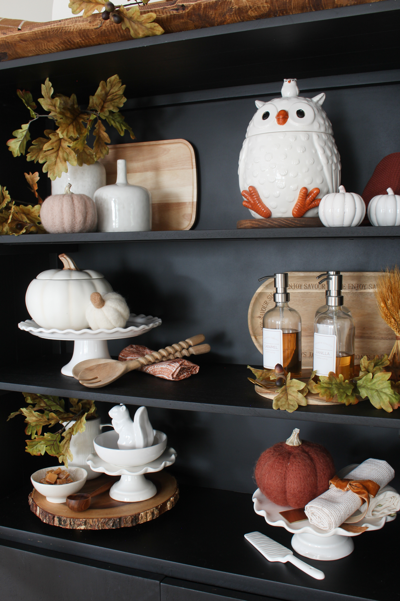 Modern black bar cabinet decorated for fall with neutral pieces, pumpkins and oak leaves.