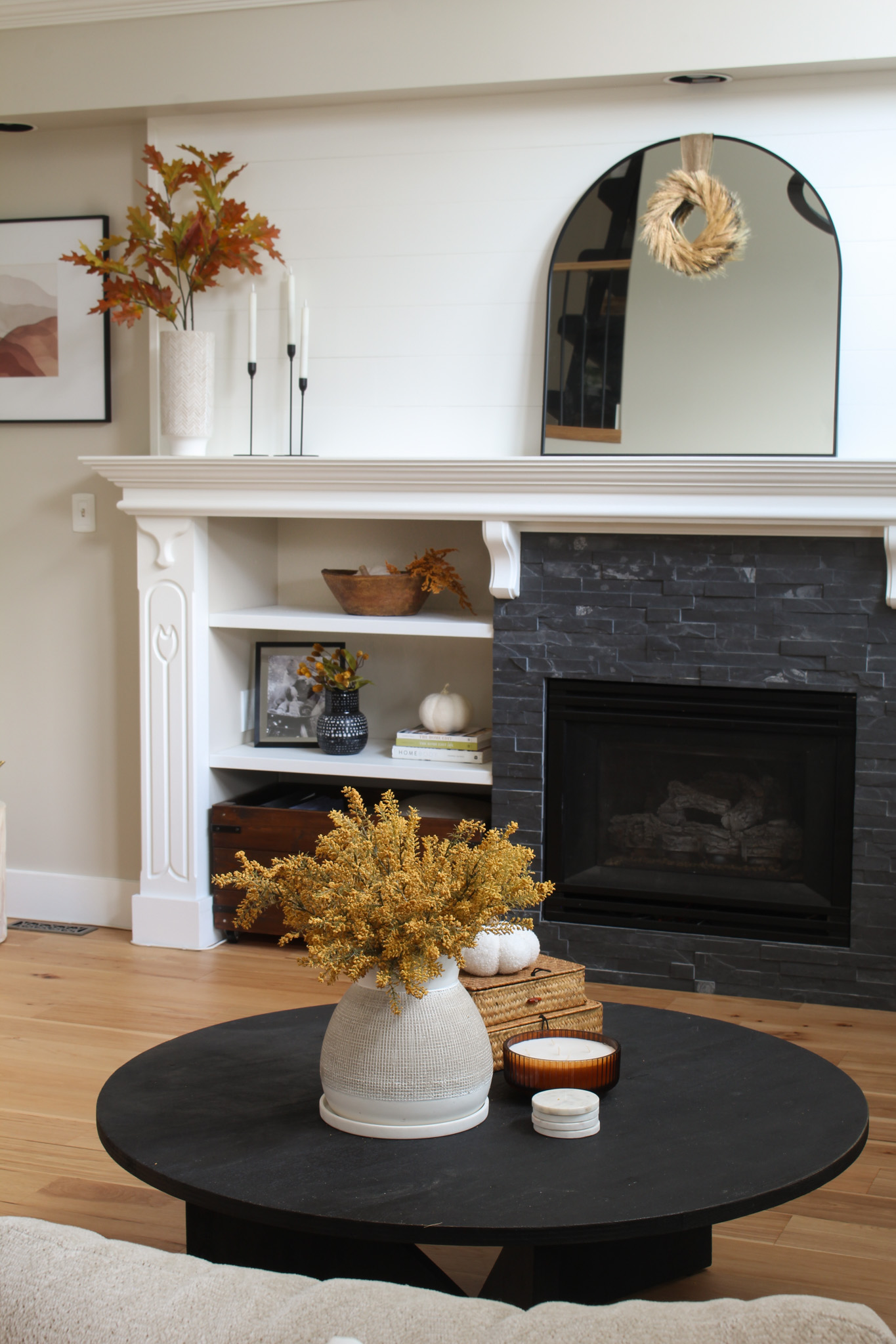 Fall living room with black sofa table and vase with faux fall blooms.