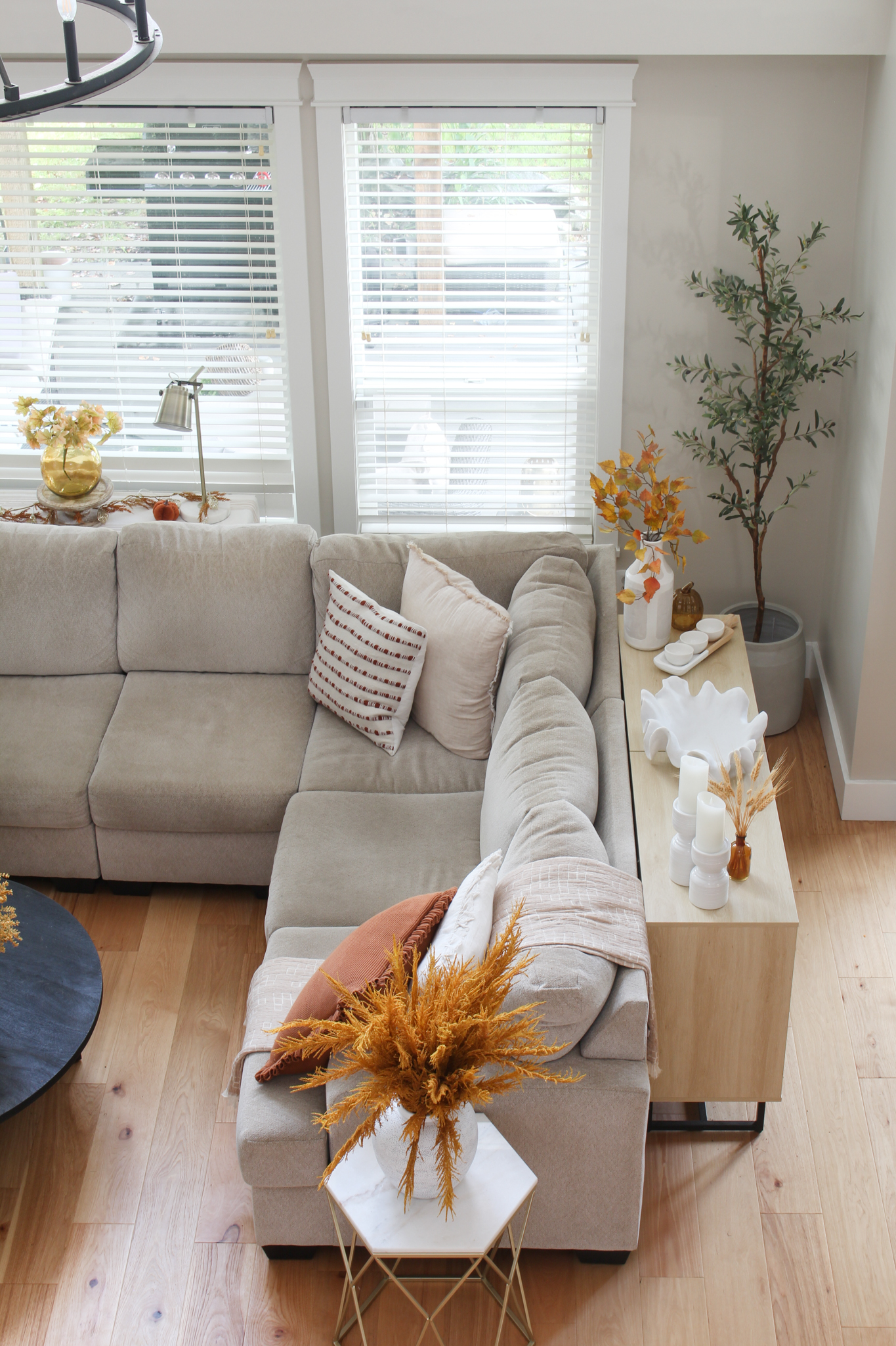 Beige sectional sofa with fall colored pillows and throw blanket.