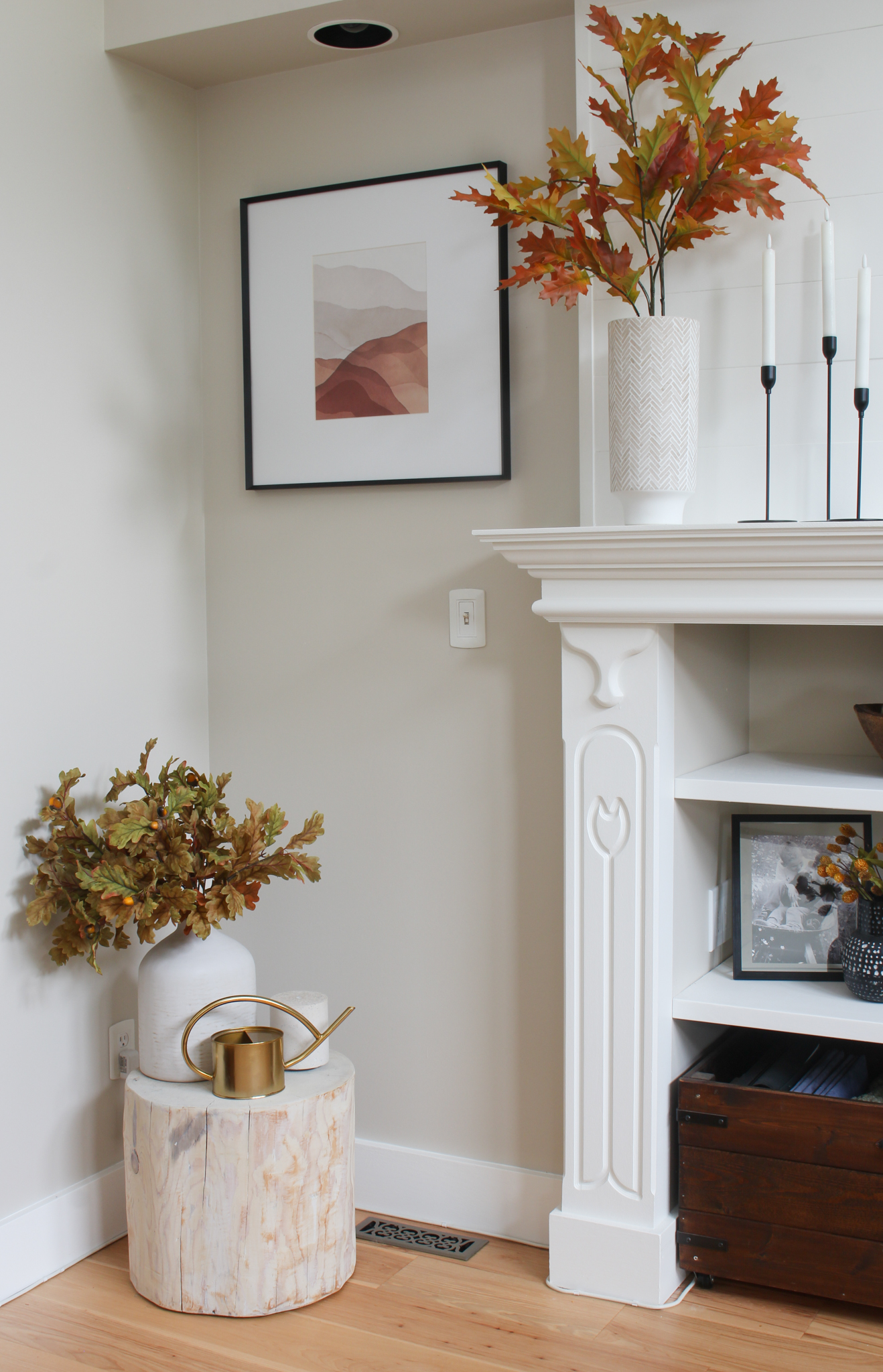 Cozy fall corner in a living room with fall artwork, faux fall stems, and a diffuser.