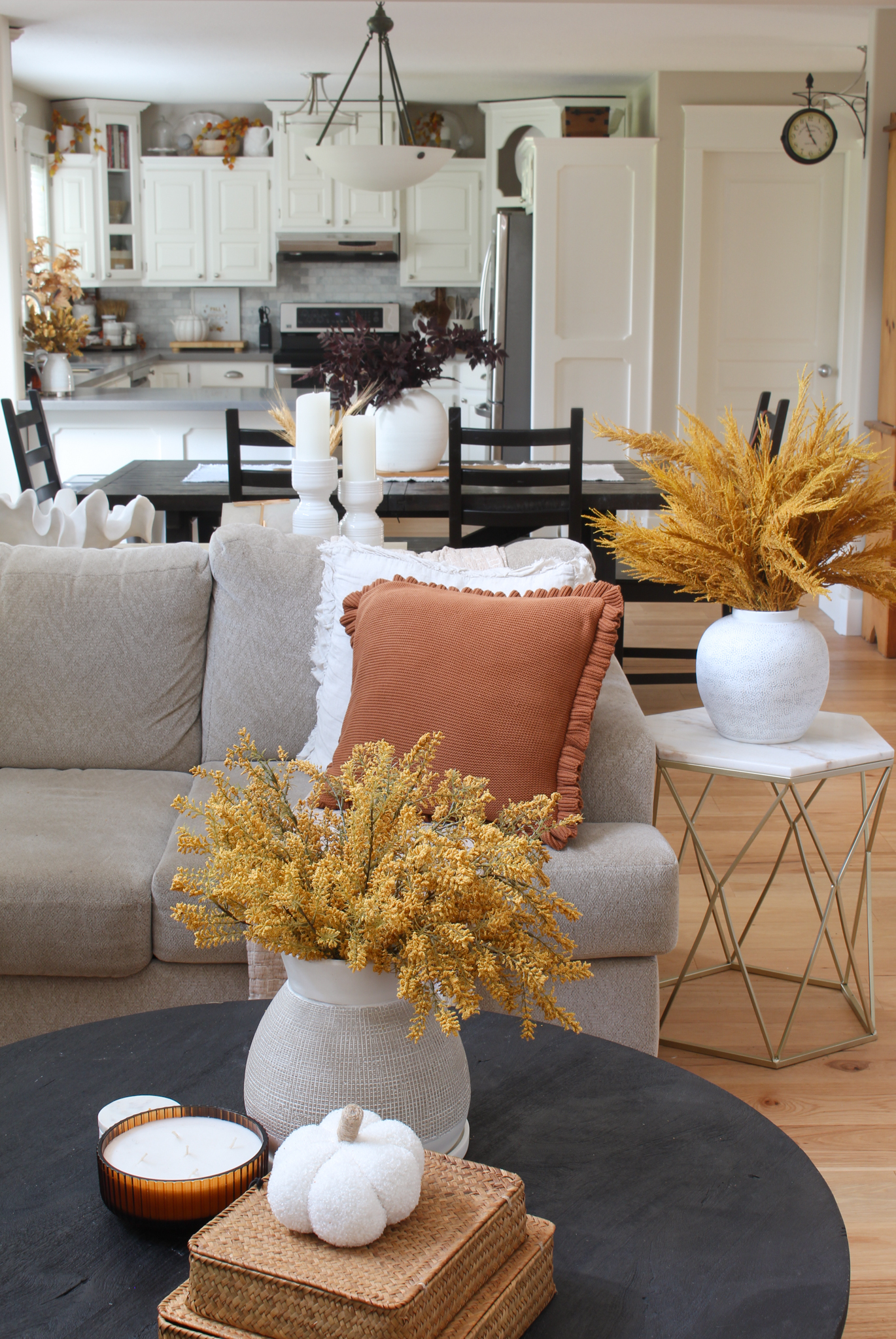 Beige sectional and black coffee table in living room decorated for fall. 