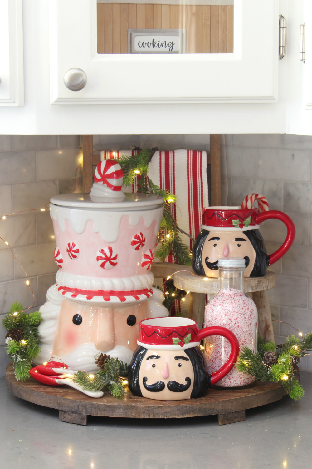 Wooden tray decorated for Christmas with nutcracker cookie jar and mugs.