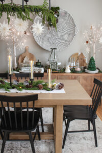 Dining room decorated for Christmas with lots of greenery, pine cones, snowflakes, and other natural elements.