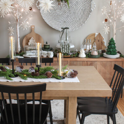 Dining room decorated for Christmas with lots of greenery, pine cones, snowflakes, and other natural elements.