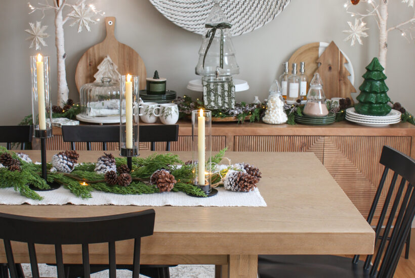 Dining room decorated for Christmas with lots of greenery, pine cones, snowflakes, and other natural elements.