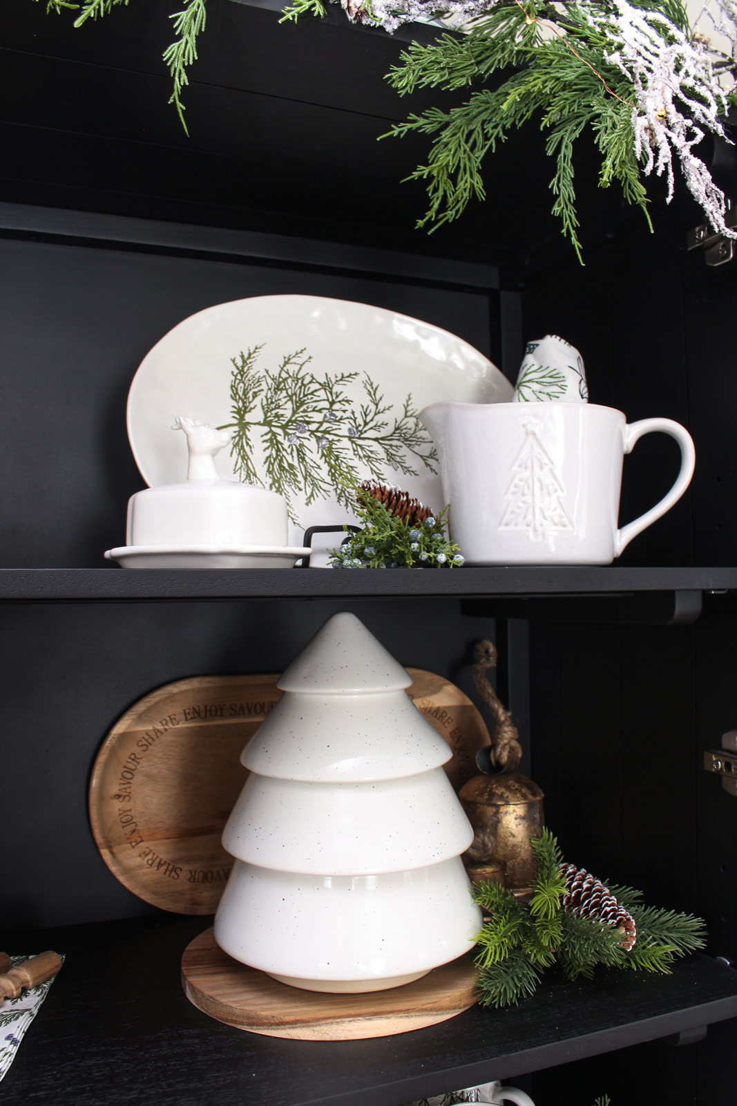 Black bar cabinet decorated for Christmas with white, forest green and wood decor pieces.