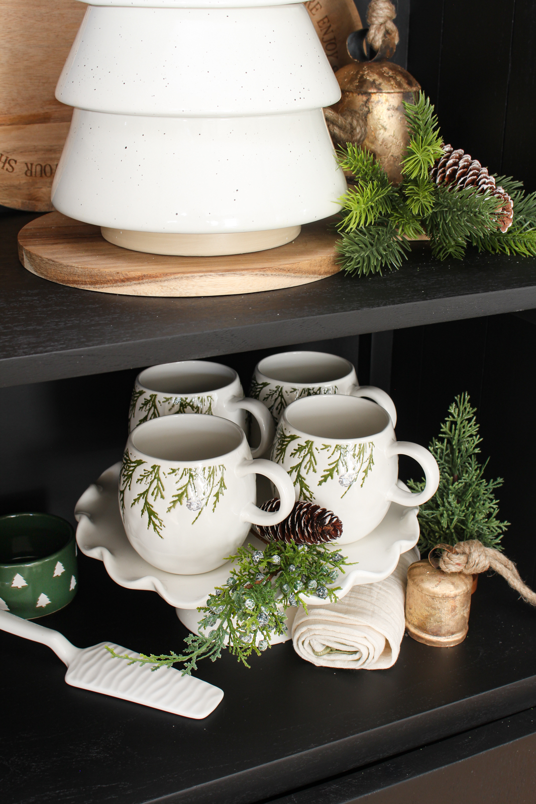 Black bar cabinet decorated for Christmas with white, forest green and wood decor pieces.