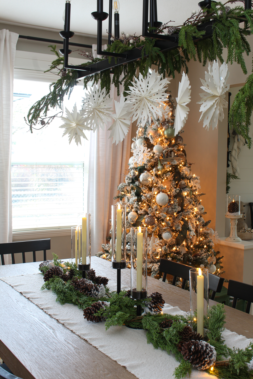 Christmas dining room with decorated Christmas table and lighted Christmas tree in the corner.