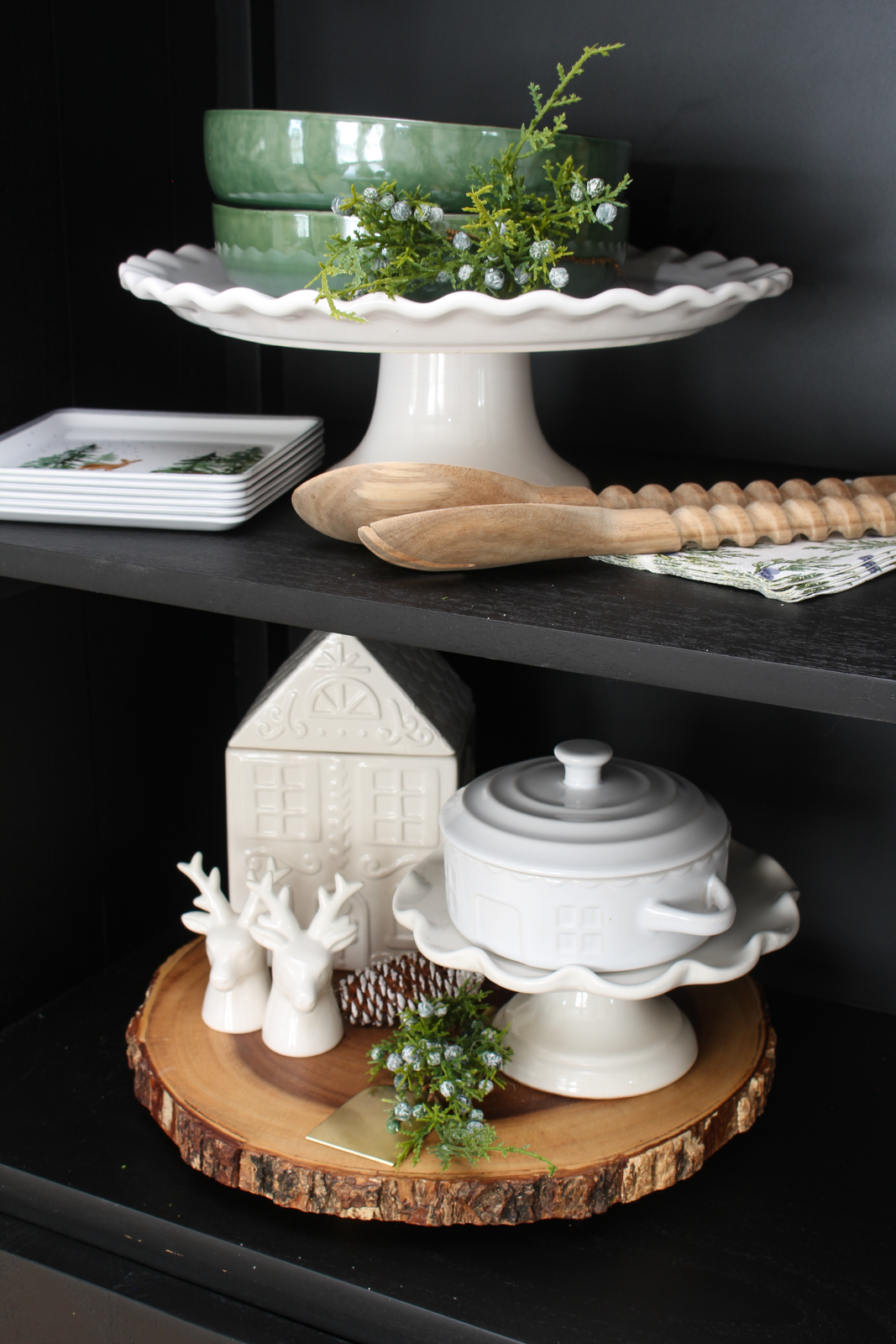 Black bar cabinet decorated for Christmas with white, forest green and wood decor pieces.